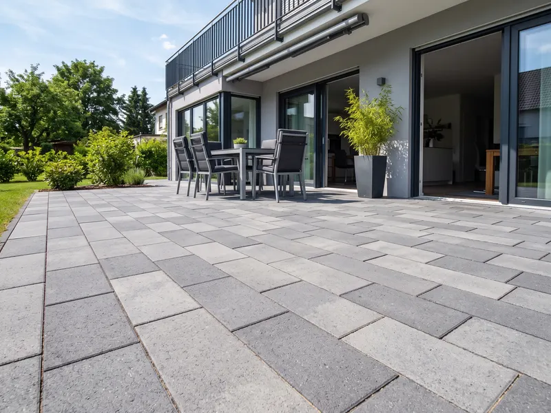 Modern gepflasterte Terrasse mit grauen Betonsteinen an einem Wohnhaus